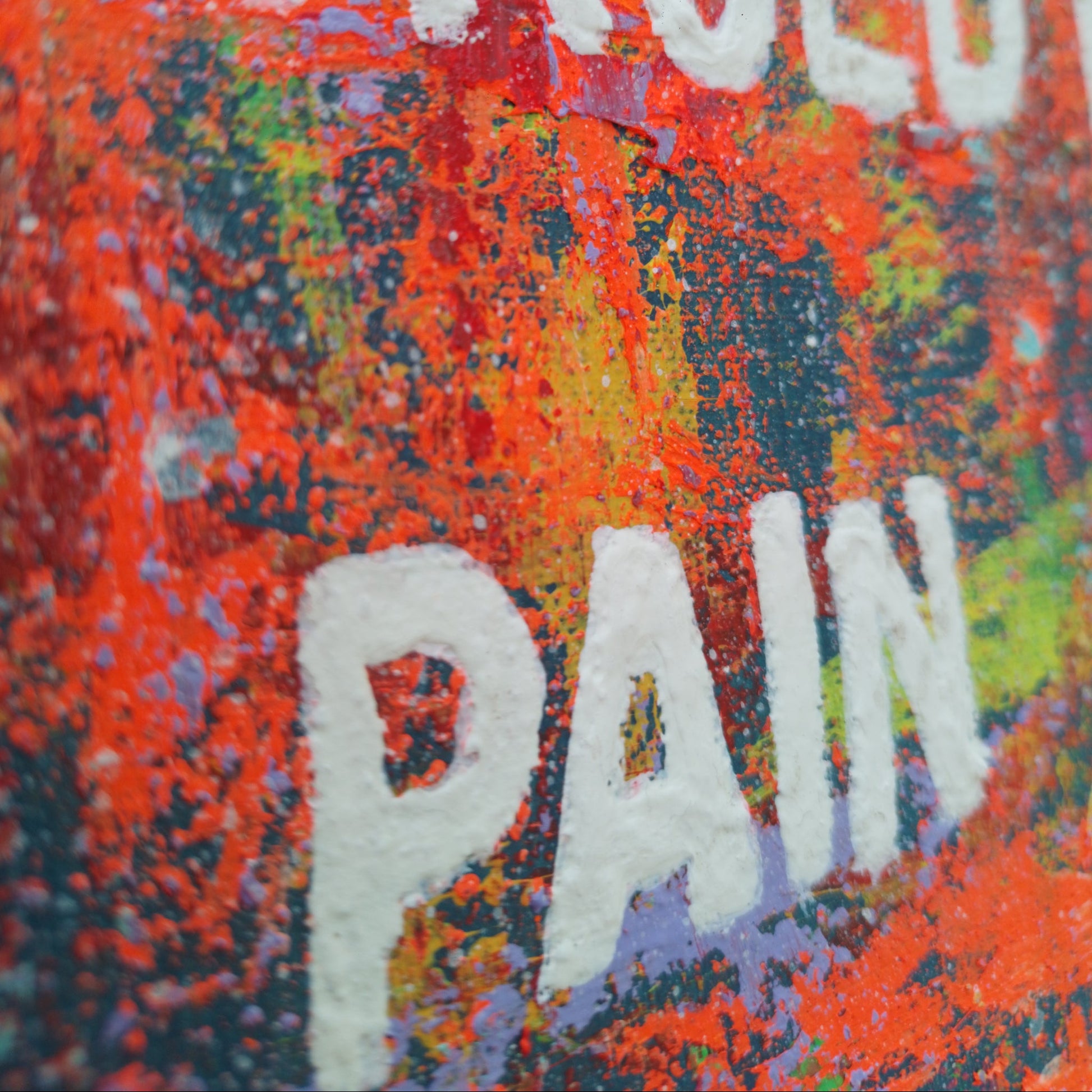 “Detail view of raised white lettering and texture in abstract expressionist painting ‘Art Is Forged in Pain."
