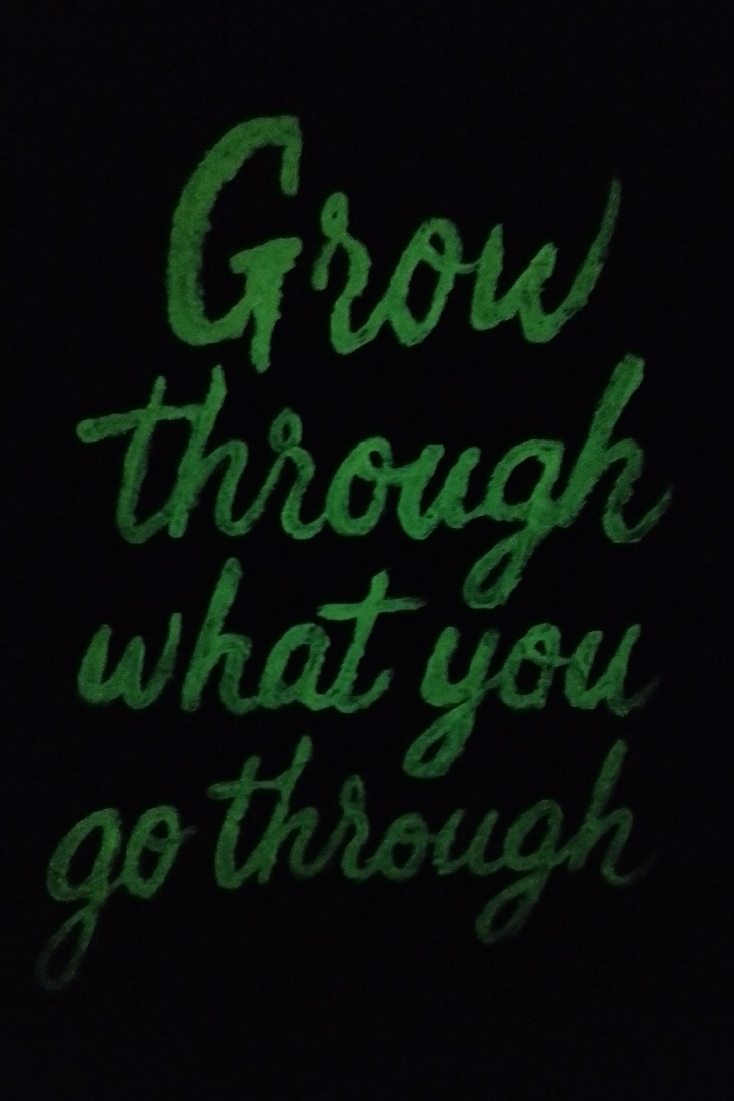 “Glow in the dark expressionism painting with motivational quote ‘Grow Through What You Go Through’ illuminated at night.”