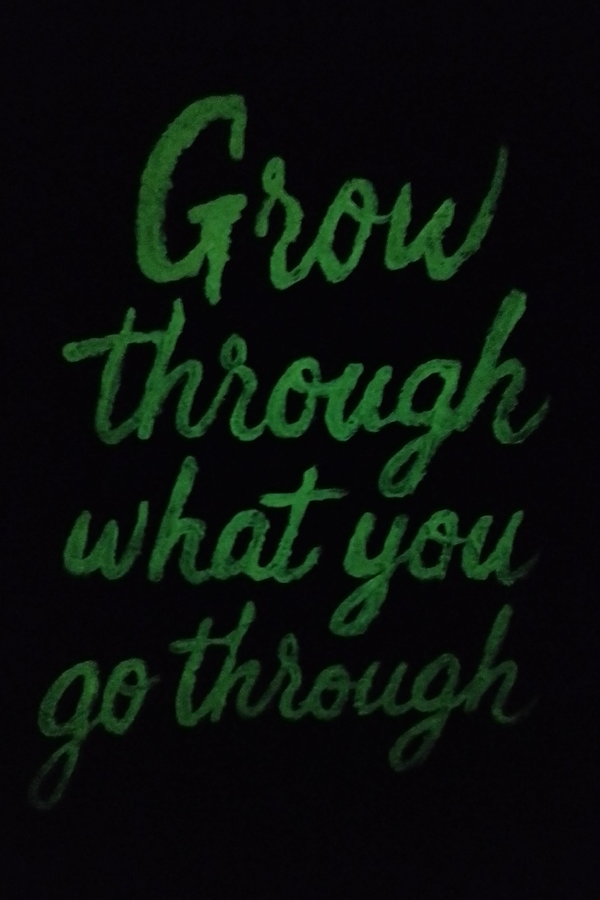 “Glow in the dark expressionism painting with motivational quote ‘Grow Through What You Go Through’ illuminated at night.”