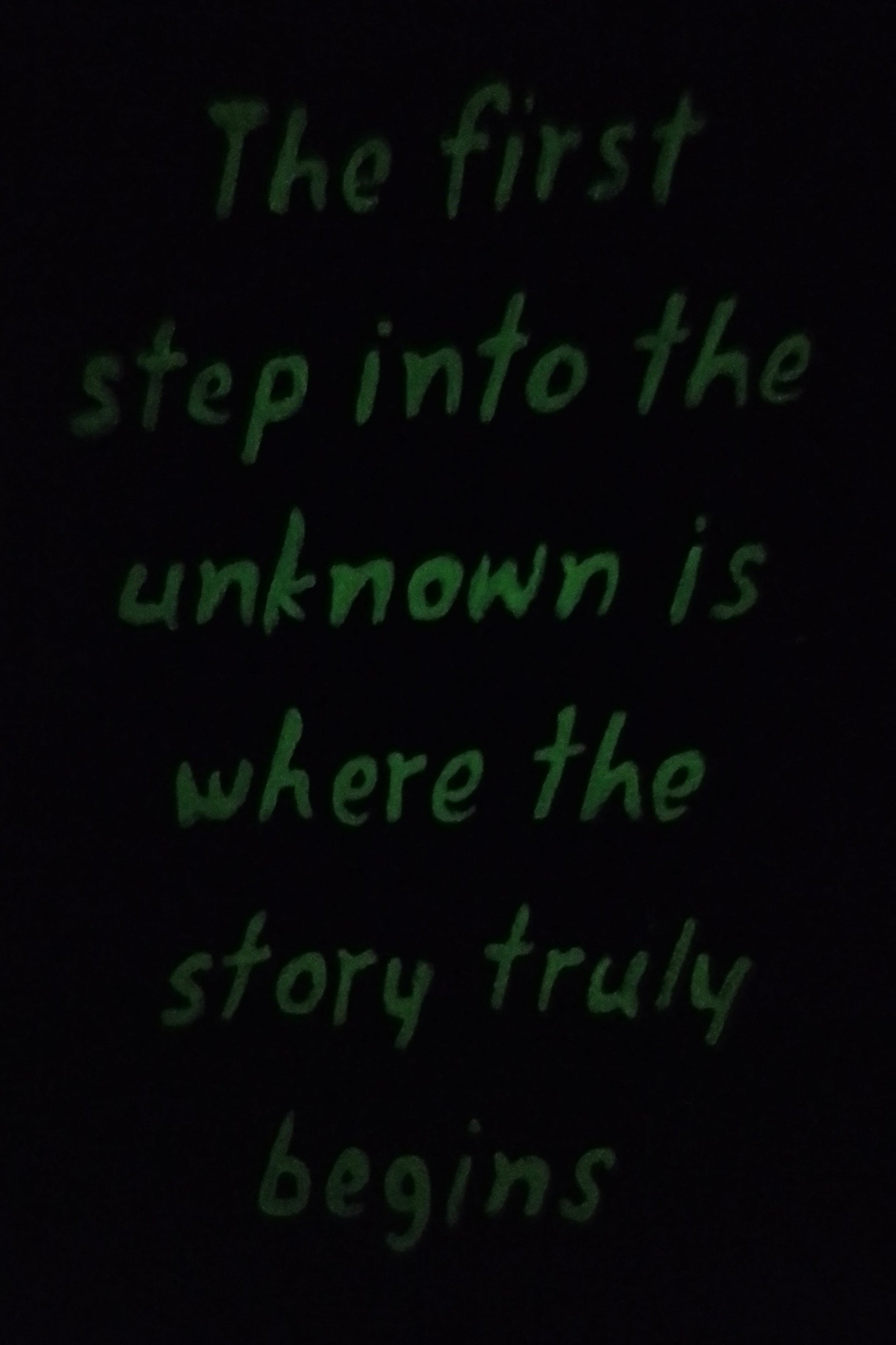 “Glow-in-the-dark version of painting with motivational quote: ‘The first step into the unknown is where the story truly begins."