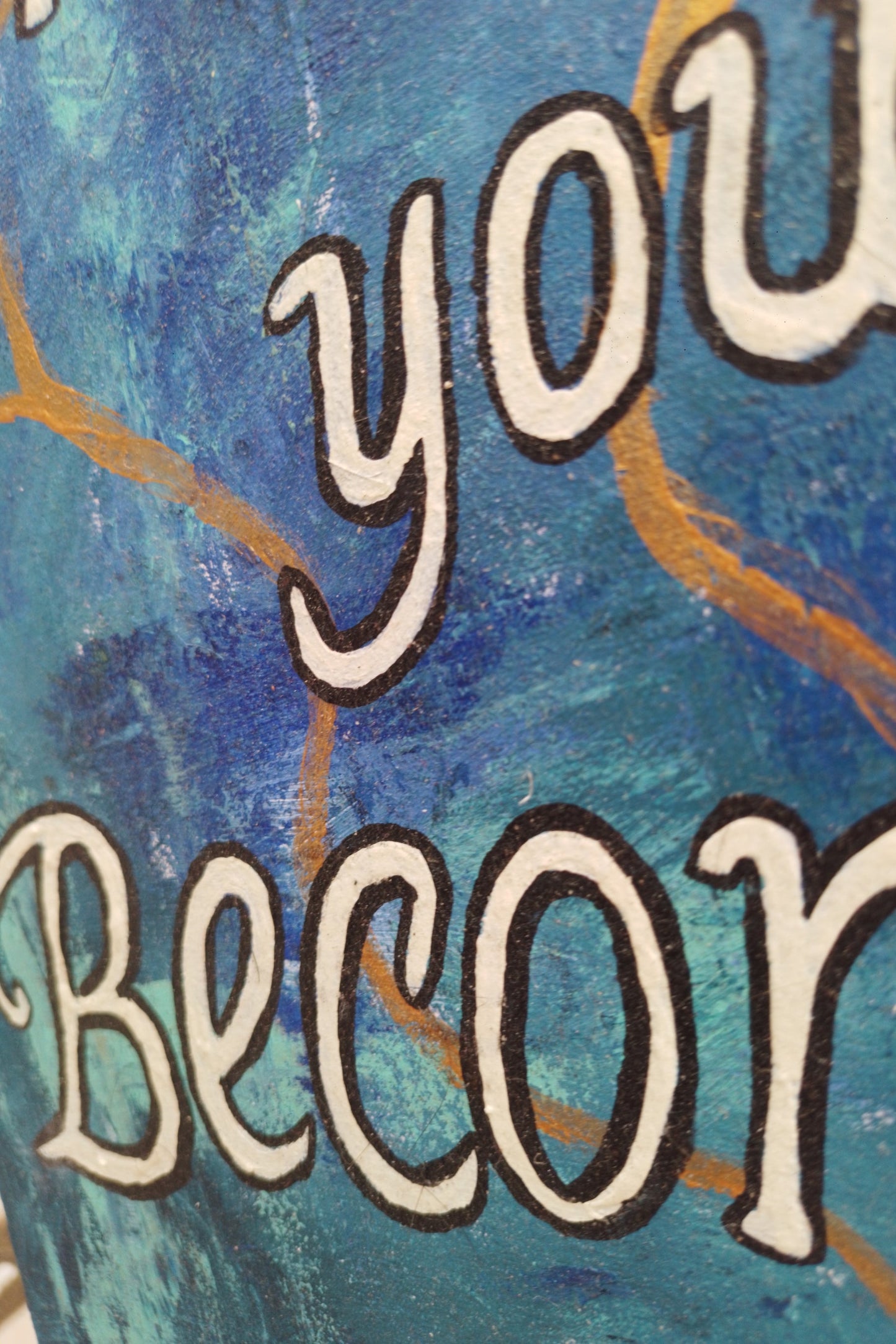 “Close-up of bold lettering on abstract expressionism painting with inspirational quote: ‘You’re not broken, you’re becoming."